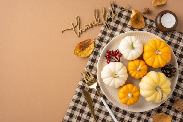 istock Top view of a Thanksgiving table setting featuring small pumpkins, autumn leaves, and a gingham napkin creating a cozy and festive atmosphere 2172678641