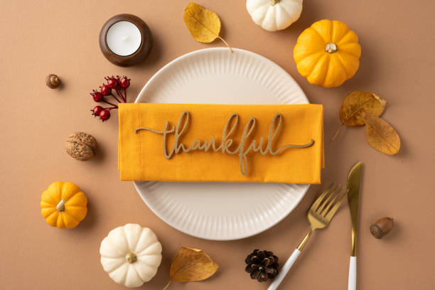 istock Elegant Thanksgiving table setting featuring a thankful note on a napkin, surrounded by autumn leaves and mini pumpkins, creating a warm holiday atmosphere 2172678664
