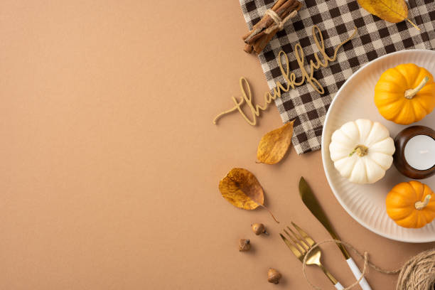 istock Autumn themed Thanksgiving table setting with small decorative pumpkins in warm colors, acorns, and a thankful sign on a plaid cloth background 2172678689