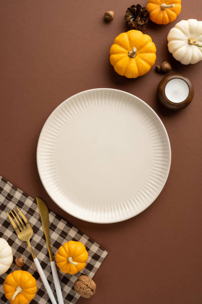 istock A festive vertical Thanksgiving table setting featuring pumpkins, a candle, and elegant cutlery on a brown background 2172678696