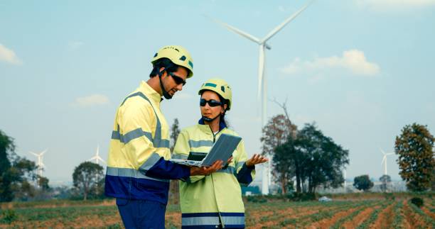 istock Renewable energy engineers are intently reviewing data on a laptop, contemplating the expansive turbine field before them. Green ecological power generation wind sustainable energy. 2172679657