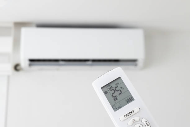 istock Adjusting air conditioner temperature with remote control. Hand holds remote control and setting comfortable temperature on climate system in apartment 2172680818