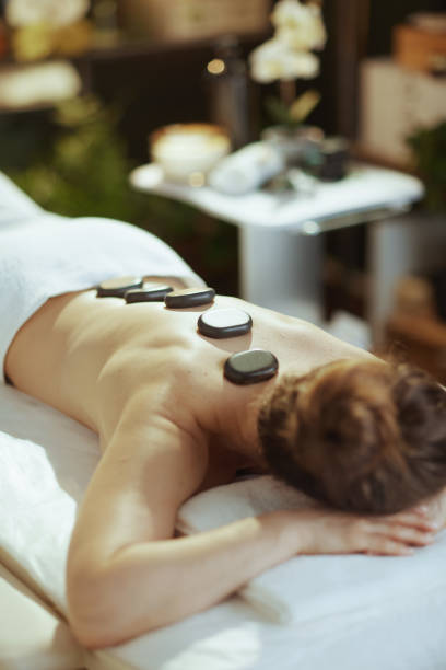 istock woman having hot stone massage and laying on massage table 2172688148