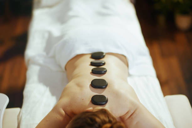 Healthcare time. Closeup on relaxed female in massage cabinet having hot stone massage and laying on massage table.