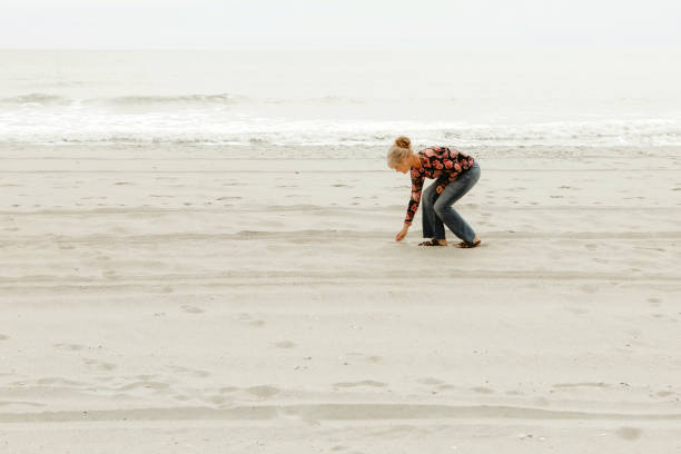 istock Woman Gathering Shells on the Beach 2172689837