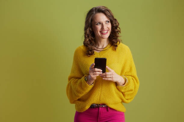 happy trendy female using smartphone against green background