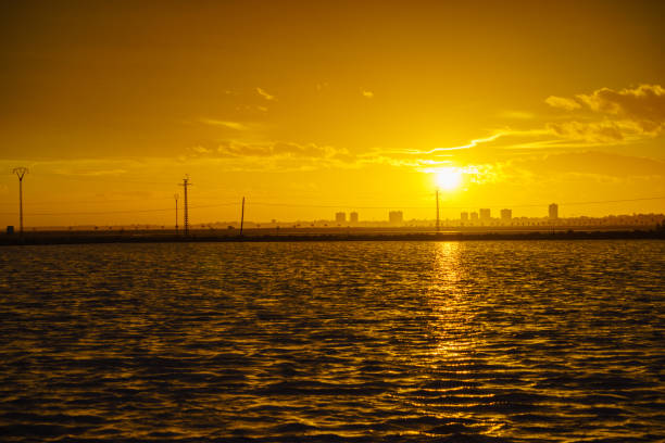 Sunset over sea coast with urban city skyline. Coastlal landscape in golden hours, San Pedro del Pinatar, Murcia Spain.