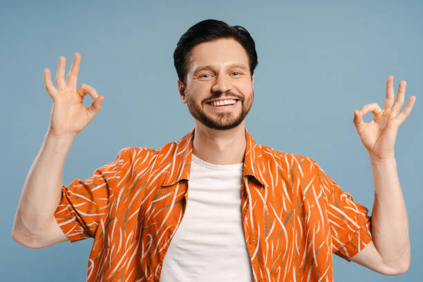 istock Happy man showing ok sign with both hands looking at camera, standing isolated on blue background 2172705879