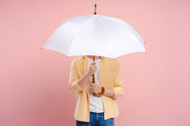 istock Young man hiding his face behind a white umbrella on a pink background 2172707769