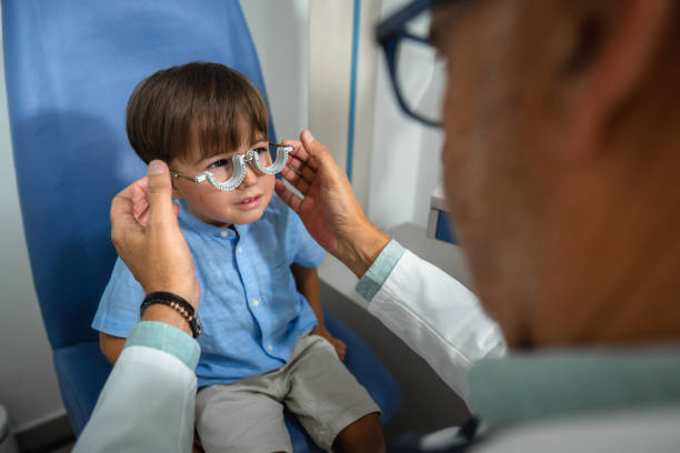 Optometrist placing trial frame on boy having eyesight examined