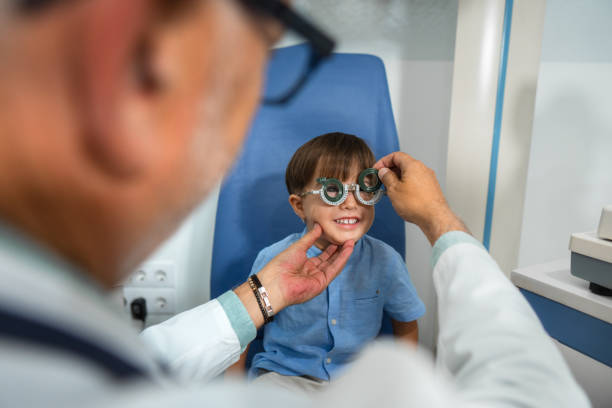 Smiling boy having his eyesight tested by an optometrist using a trial frame