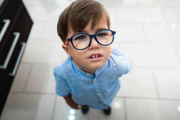 The smiling face of a little boy with glasses in the park