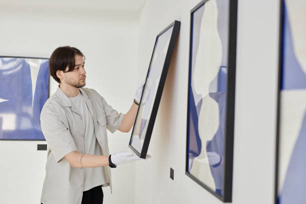 istock Asian Man as Art Curator Hanging Paintings 2172726721