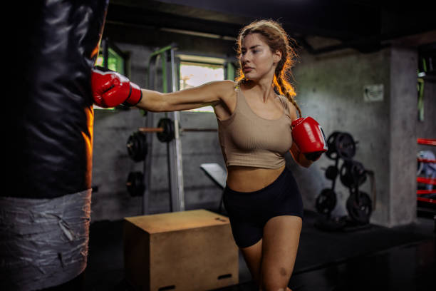 istock Skilled female boxer practices hitting heavy bag 2172729304