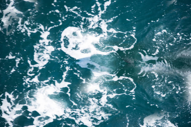 Blue water with ripples on the surface. Defocus blurred transparent blue colored clear calm water surface texture with splashes and bubbles. Water waves with shining pattern texture background.