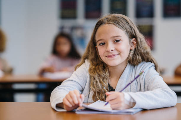 istock Young girl smiles while writing in a notebook during class time 2172736825