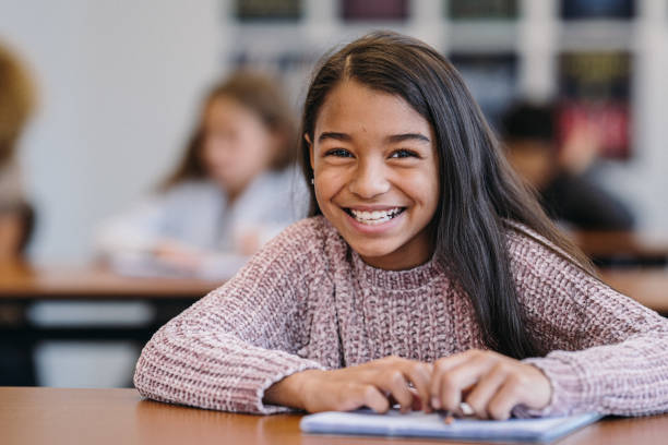 Cute girl smiles while doing schoolwork in class