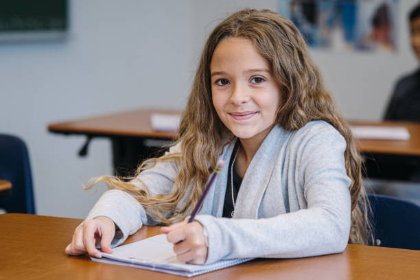 istock Young girl smiles while writing in a notebook during class time 2172736878