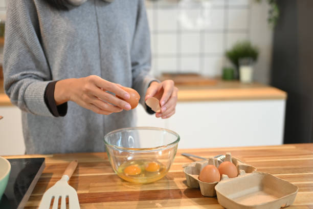 istock Young woman cracking an egg into a mixing bowl, preparing breakfast in her kitchen 2172740969