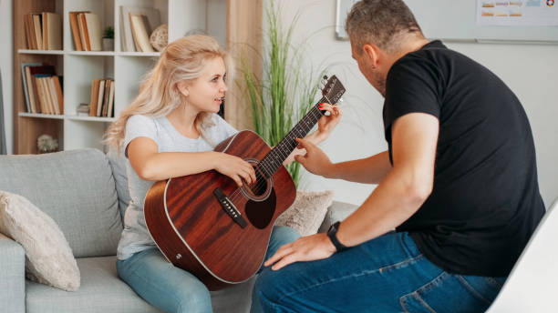 istock Guitar playing female student home courses male 2172743779