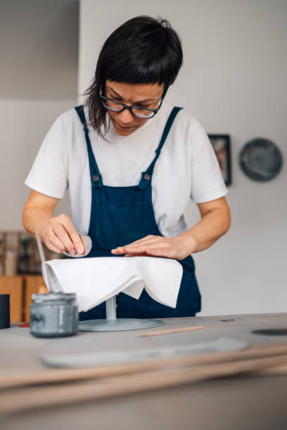 istock Focused pottery designer using pottery tool for flattening clay surface 2172744464