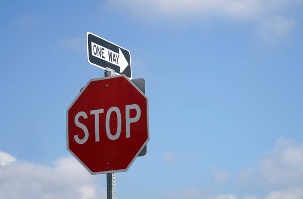 stop sign and one way sign with sky background