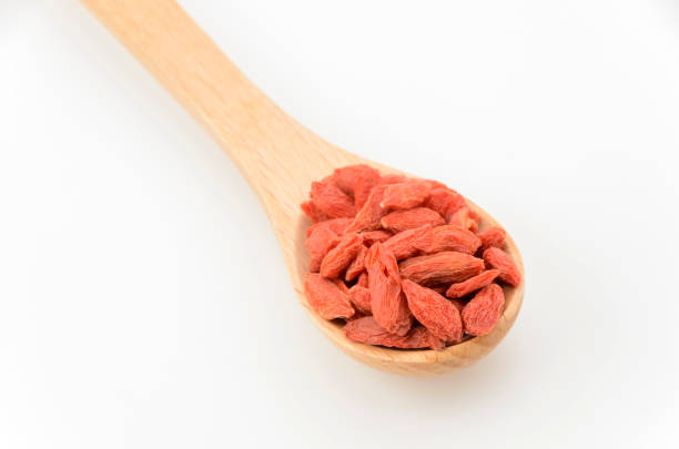 Dried goji berries on a wooden spoon on white background