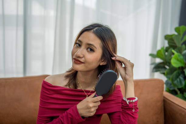 Portrait of an attractive young Asian woman combing her hair at home.