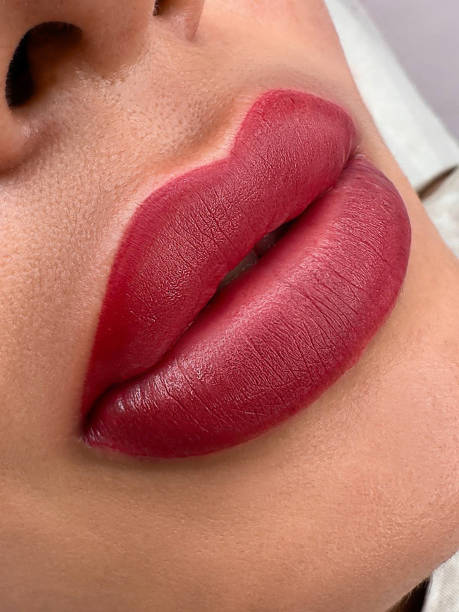 istock permanent  womans lips tattoo close up, lipstick effect make up, the lips after a tattoo with a coloring pigment 2172759575