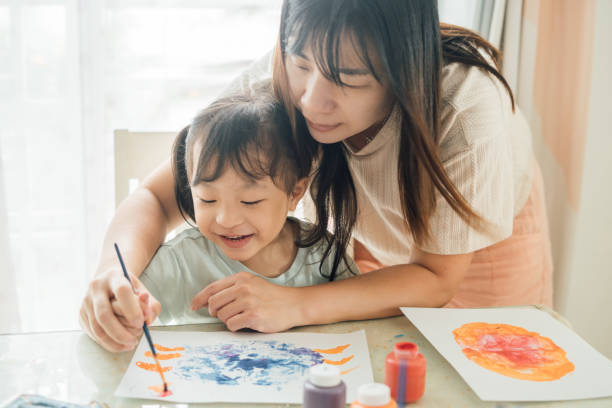 istock Mother Engaging Twin Daughters in Creative Painting and Leaf Stamping Activity 2172760865