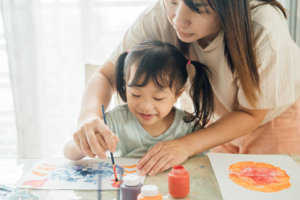 istock Mother Engaging Twin Daughters in Creative Painting and Leaf Stamping Activity 2172760888