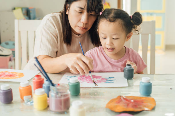istock Mother Engaging Twin Daughters in Creative Painting and Leaf Stamping Activity 2172761040