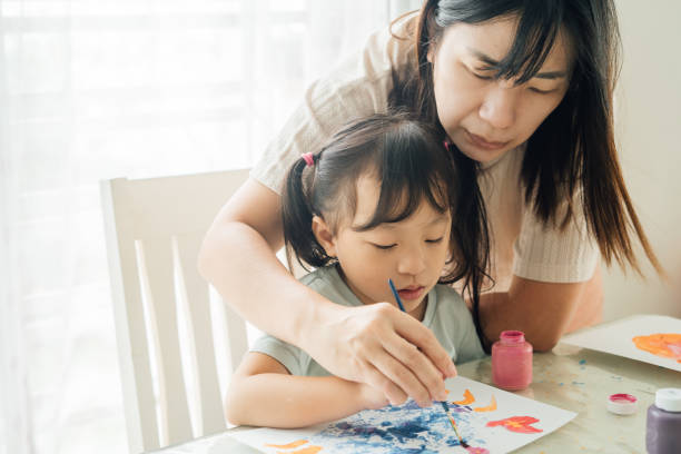istock Mother Engaging Twin Daughters in Creative Painting and Leaf Stamping Activity 2172761552