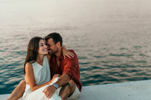 Couple sitting together on the promenade in golden sunlight. Copy space