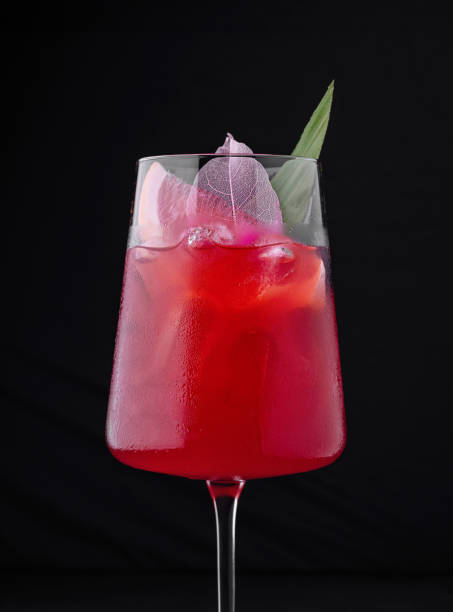 istock Red cocktail standing on black background with ice and leaf garnish 2172773207