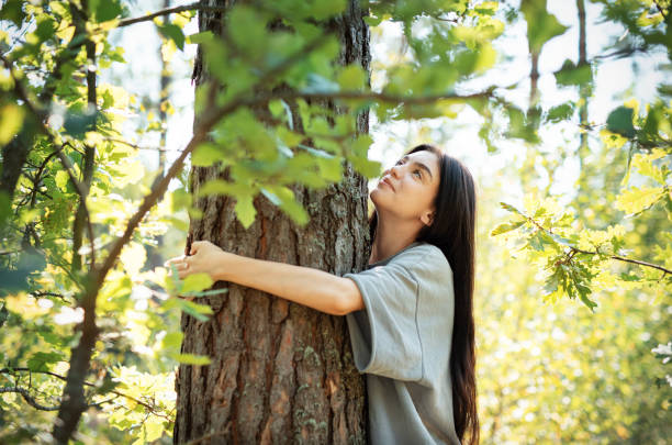 istock Young woman embracing a tree while enjoying nature in a sunlit forest during summer 2172777378