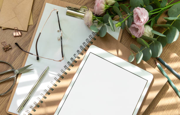 istock Stationery workspace with a blank tablet, notebook, and flowers on a wooden table, perfect for creative planning in natural light 2172777515