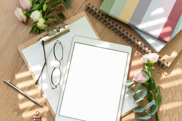istock Stationery workspace with a blank tablet, notebook, and flowers on a wooden table, perfect for creative planning in natural light 2172777563