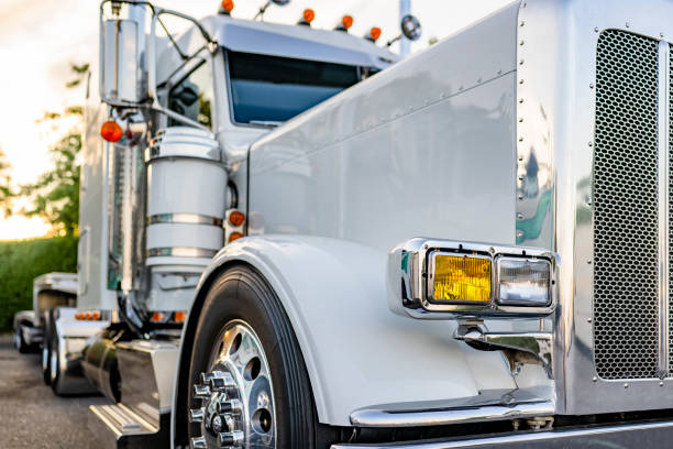 istock Classic powerful big rig white semi truck tractor with chrome parts and empty step deck semi trailer standing on the truck stop parking lot at twilight time for the truck driver rest 2172778869
