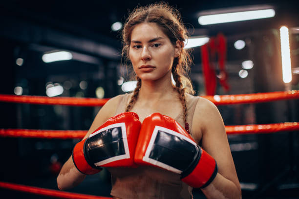 Determined female boxer stands firm with gloves.