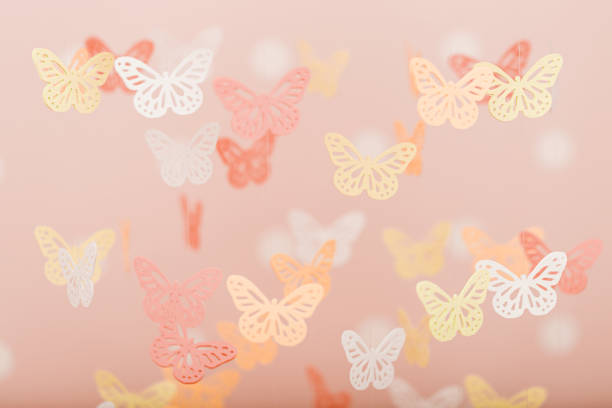 Many little gentle butterfly-shaped toys hanging over the child's crib. The pink background is used for greeting cards or invitations to baby parties.