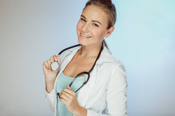 Portrait Of Female Doctor Holding Digital Tablet Against White Background