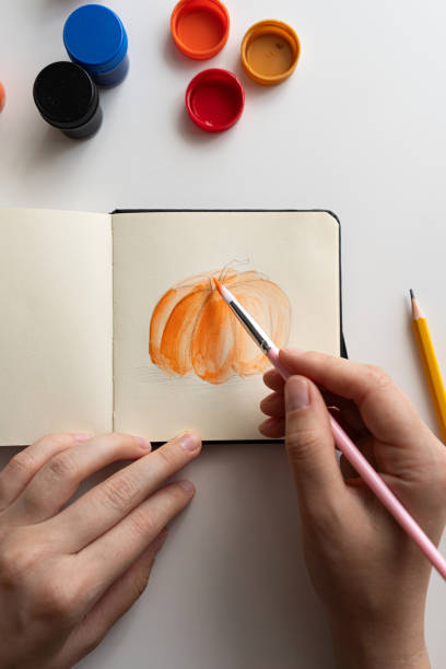istock Painting a pumpkin sketch in a notebook with gouache 2172792980