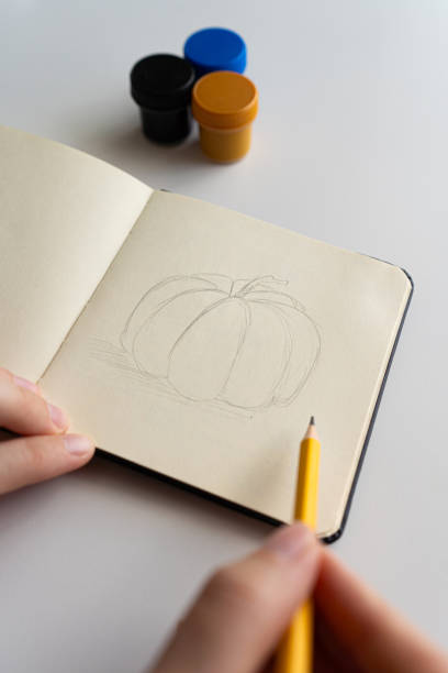 istock Starting a pumpkin sketch in a notebook with gouache 2172792997