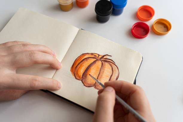 istock Painting a pumpkin sketch in a notebook with gouache 2172793043