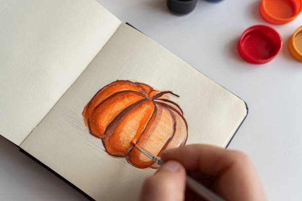 istock Finalizing a pumpkin painting with gouache in a sketchbook 2172793078