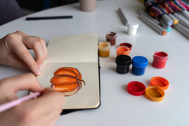 istock Finalizing a pumpkin painting with gouache in a sketchbook 2172793116