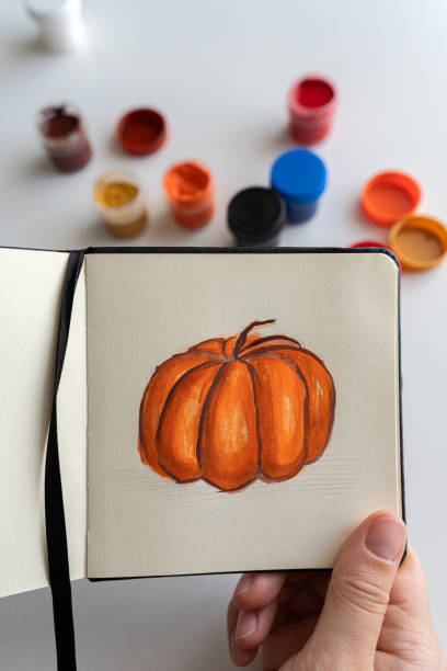 istock Finalizing a pumpkin painting with gouache in a sketchbook 2172793193