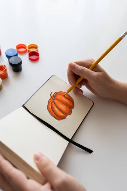 istock Finalizing a pumpkin painting with gouache in a sketchbook 2172793196