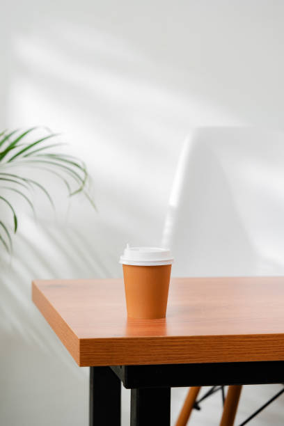 istock A disposable coffee cup on a wooden table beside a leafy plant 2172793232